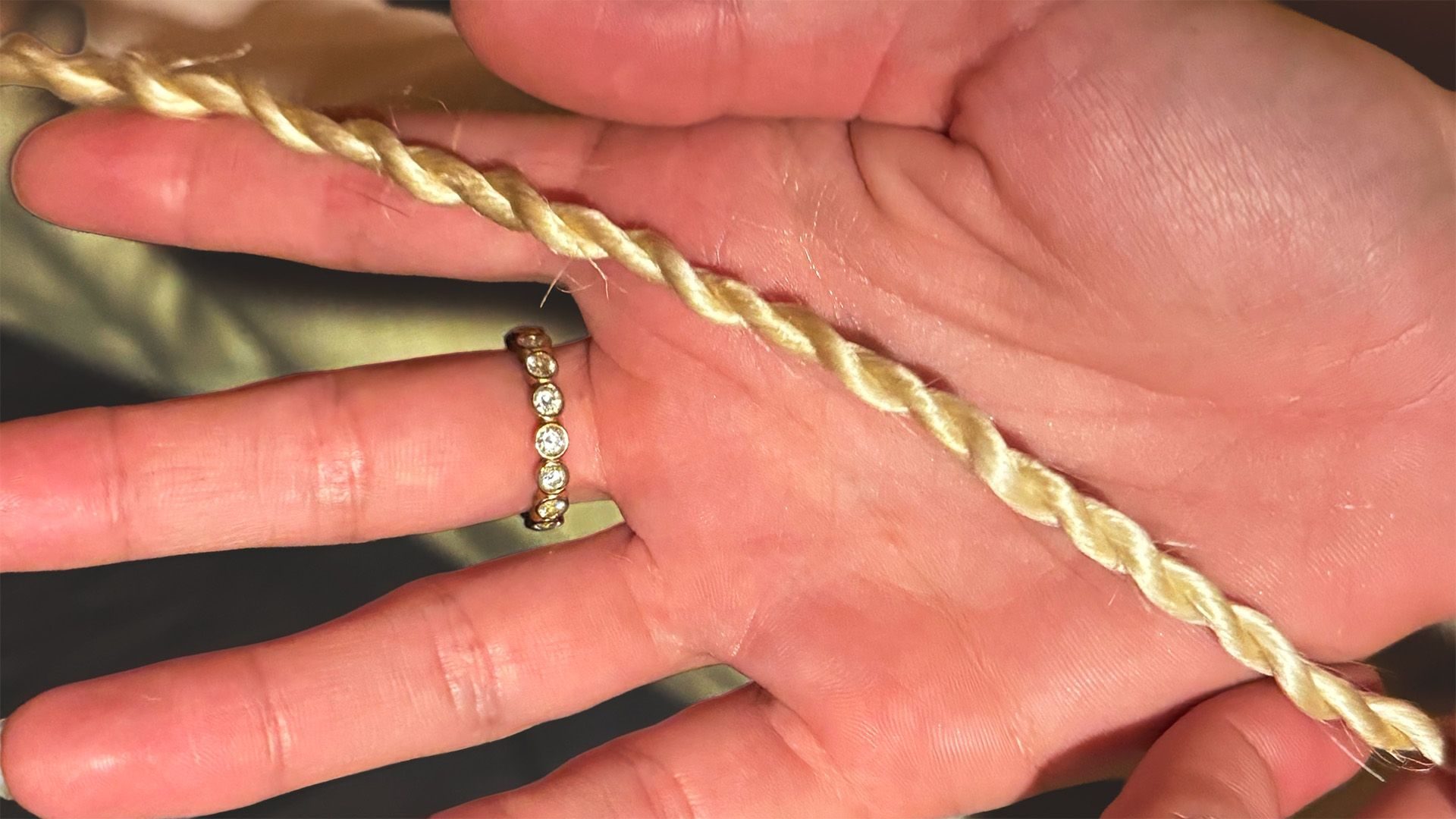 A length of rope twisted from tree bark, held in an open hand