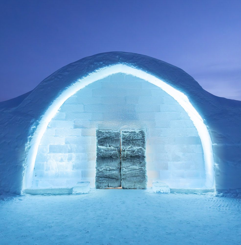 The glowing arched entrance of the Ice Hotel at dusk