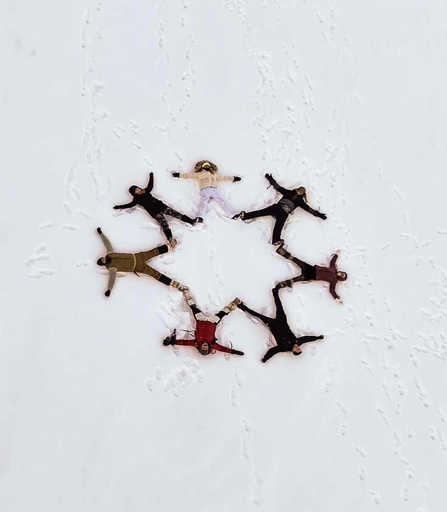 Guests lying in a circle in fresh snow, seen from above